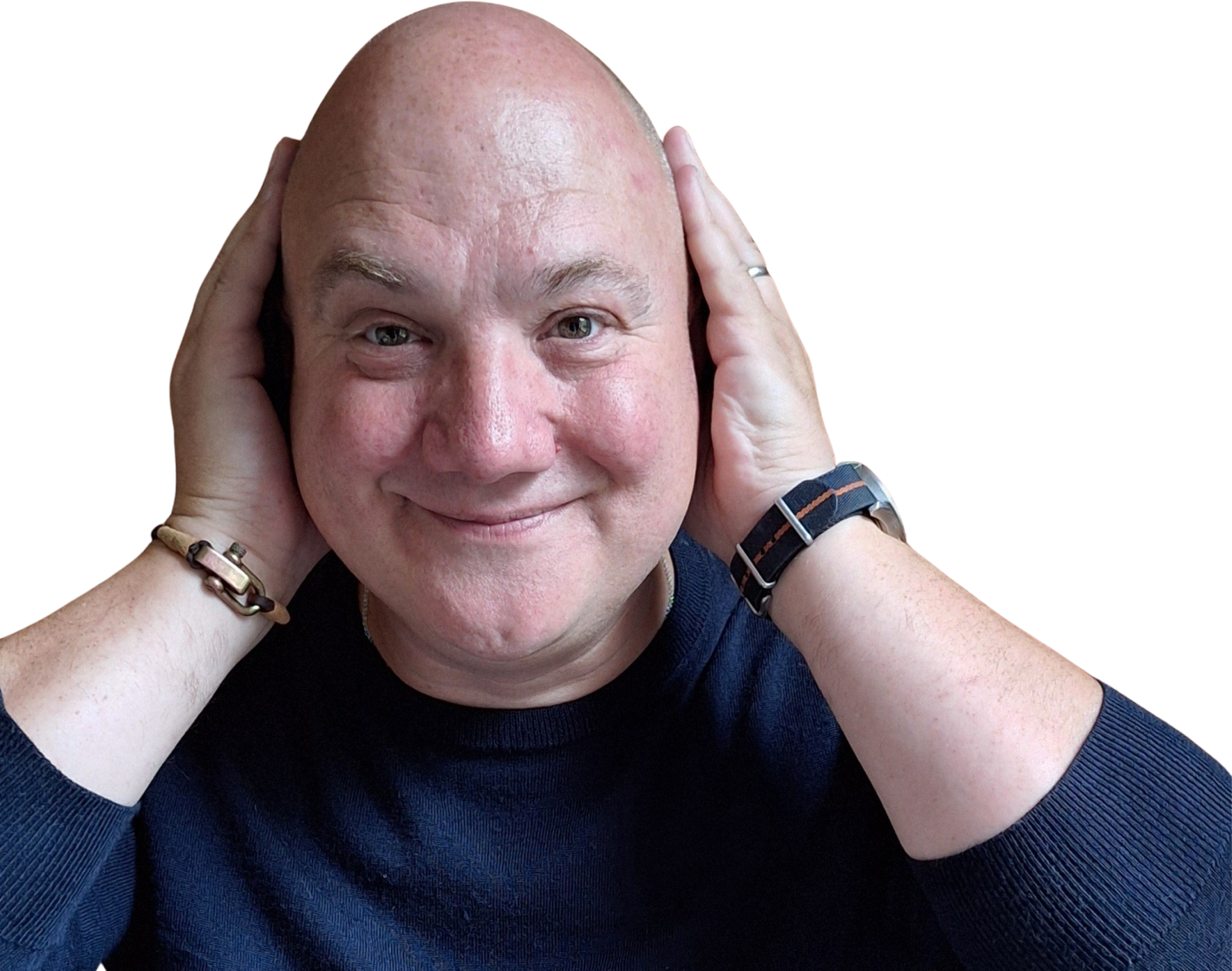 A smiling bald man wearing a dark sweater holds both hands to the sides of his head. He is wearing a bracelet on one wrist and a watch on the other.