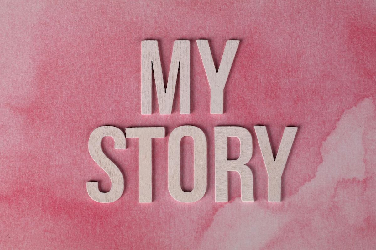The words MY STORY in large, light-colored wooden letters are placed on a pink watercolor background, hinting at a personal journey—perhaps inspired by The Trouble with Heroes.